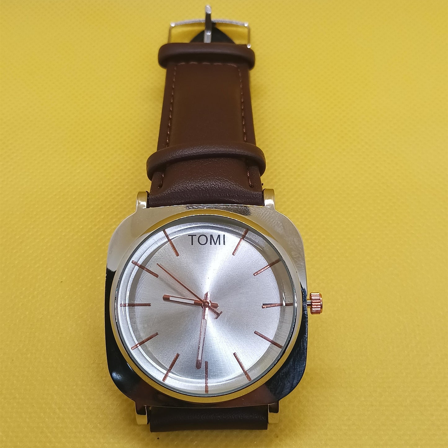 Watch with a brown leather strap on a yellow background