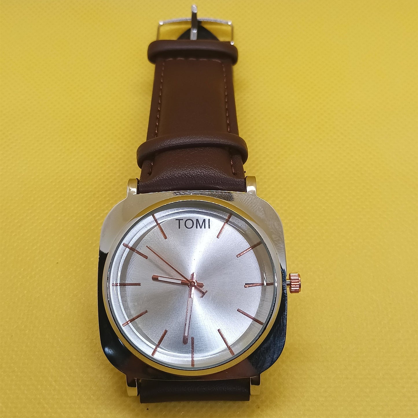 Watch with a brown leather strap on a yellow background