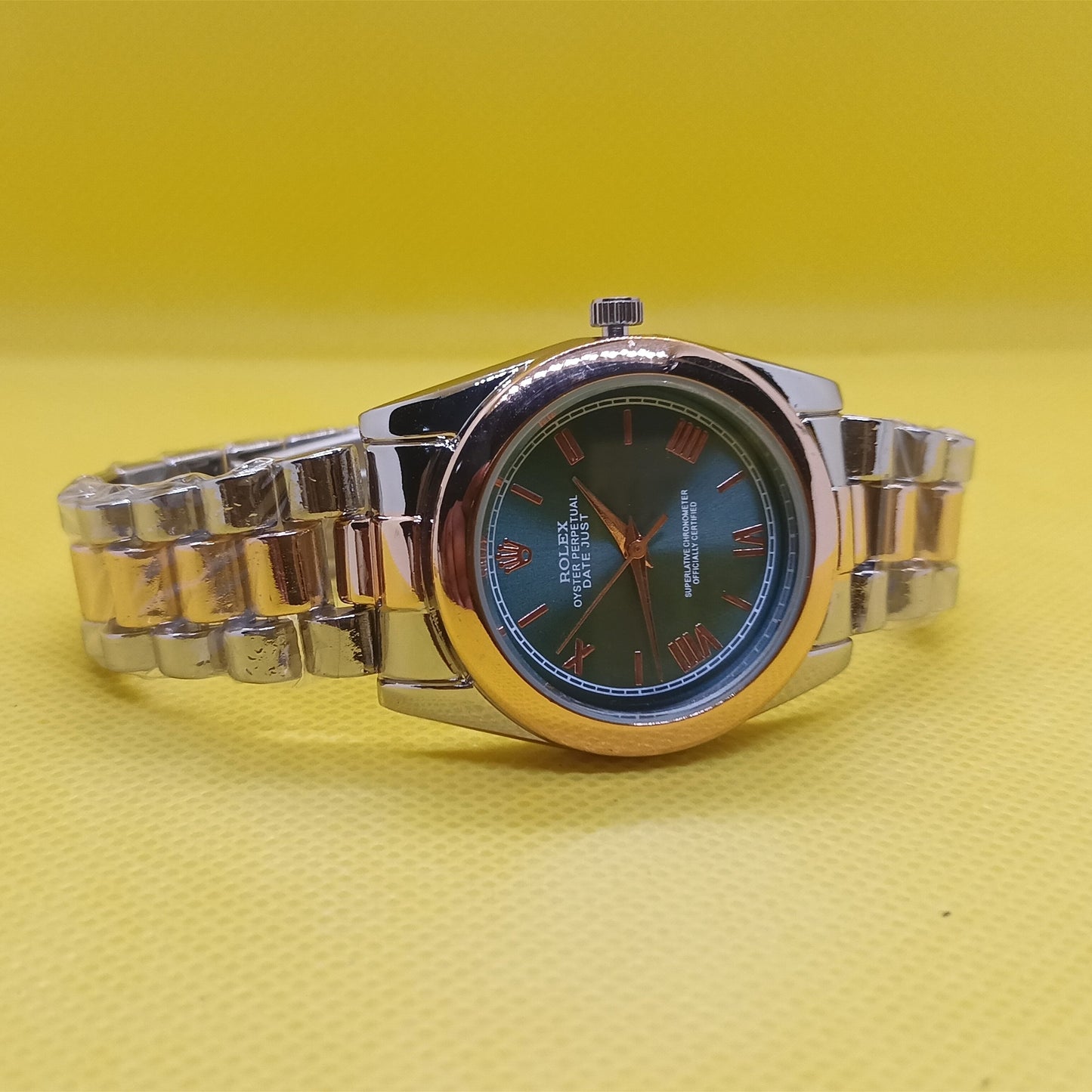 Silver watch with a dark face on a yellow background