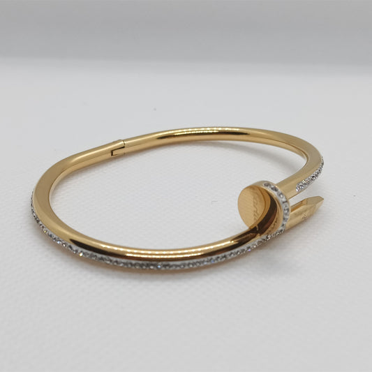 Gold bracelet with small stones on a light gray background