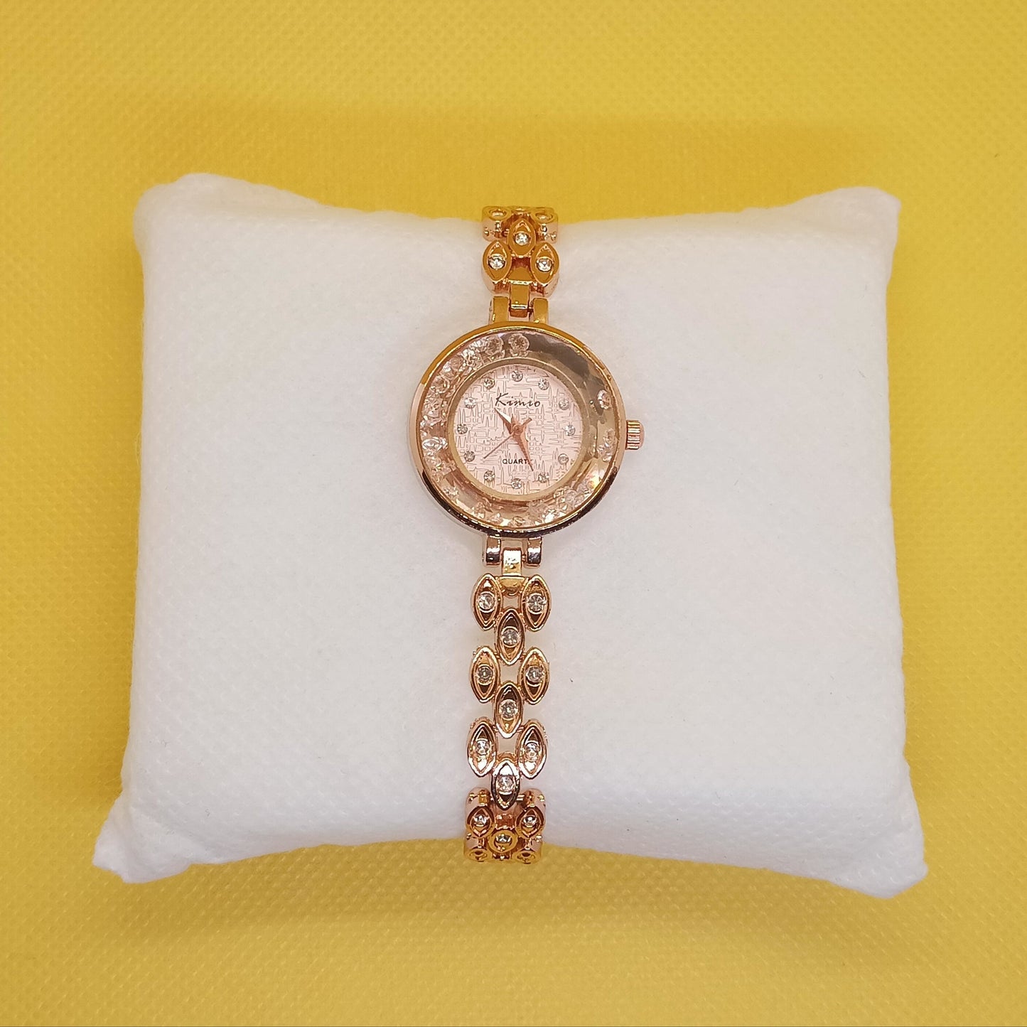 Gold wristwatch with diamond-studded chain on a yellow background