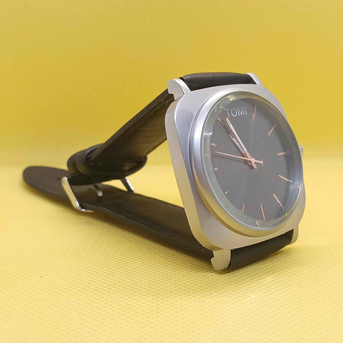 Wristwatch with black strap and silver case on a yellow background