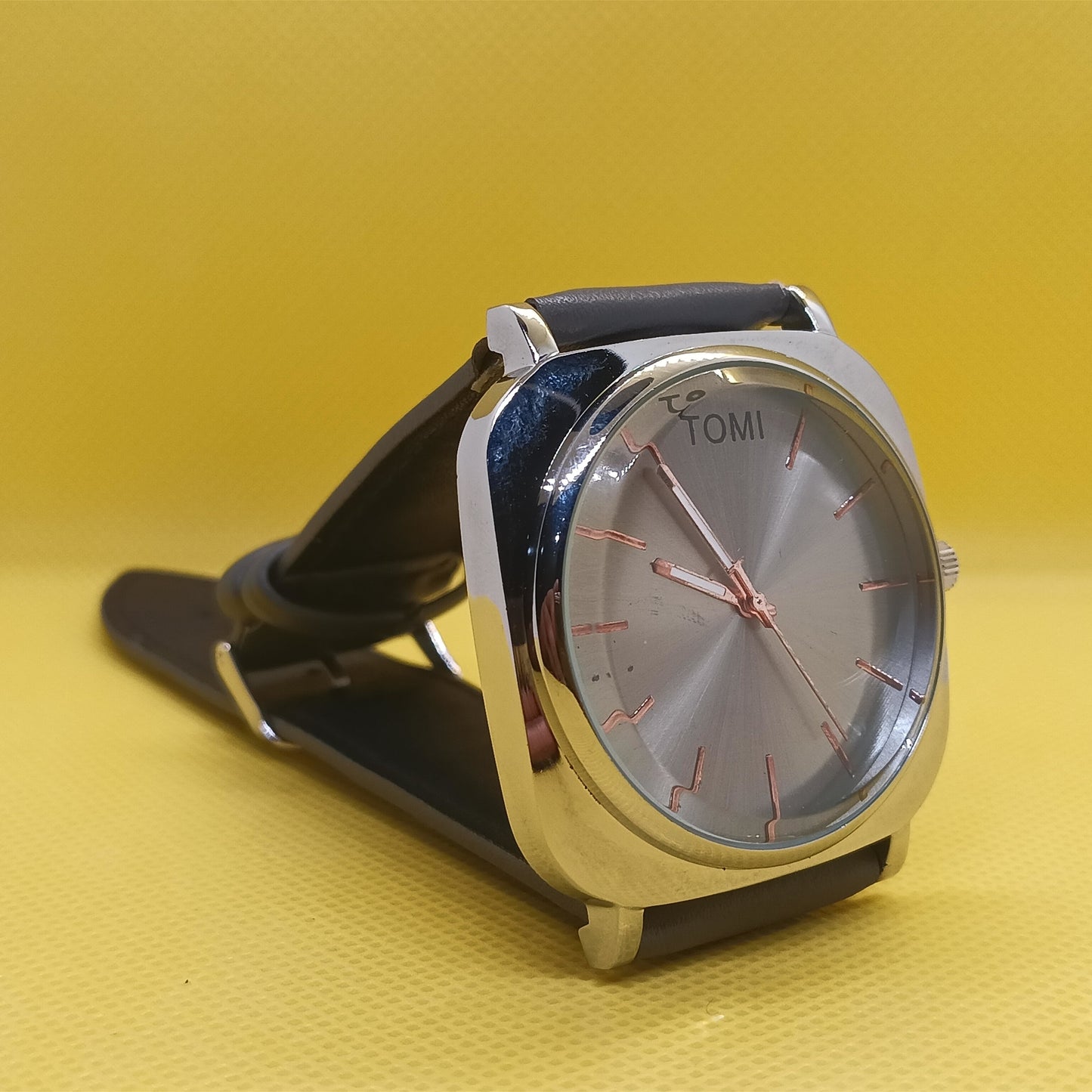 Wristwatch with black strap and silver case on a yellow background