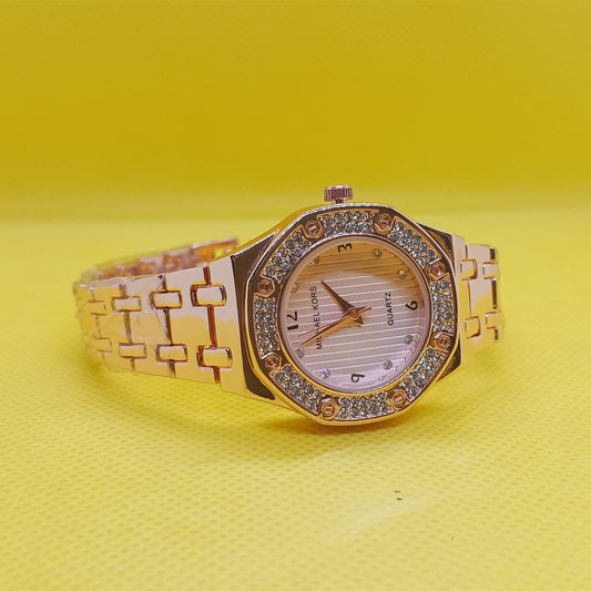 Gold wristwatch with gemstone accents on a yellow background