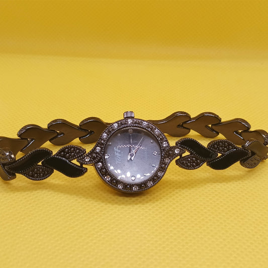 Decorative watch with leaf-like design on a yellow background