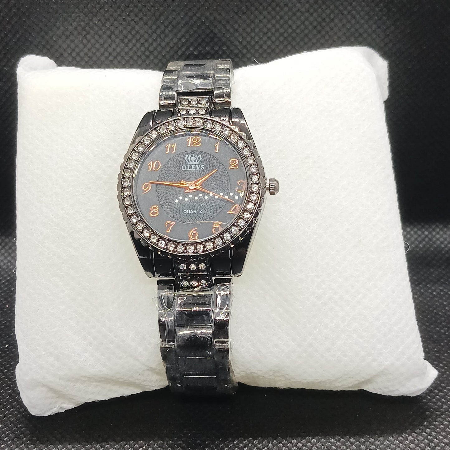 Black watch with a detailed face on a white cushion against a dark background