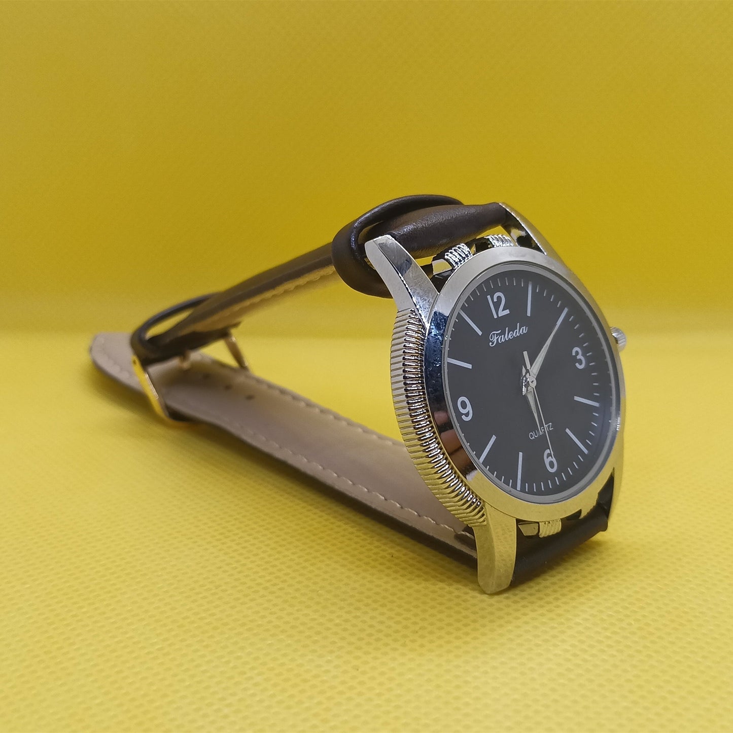Watch with brown leather strap on a yellow background