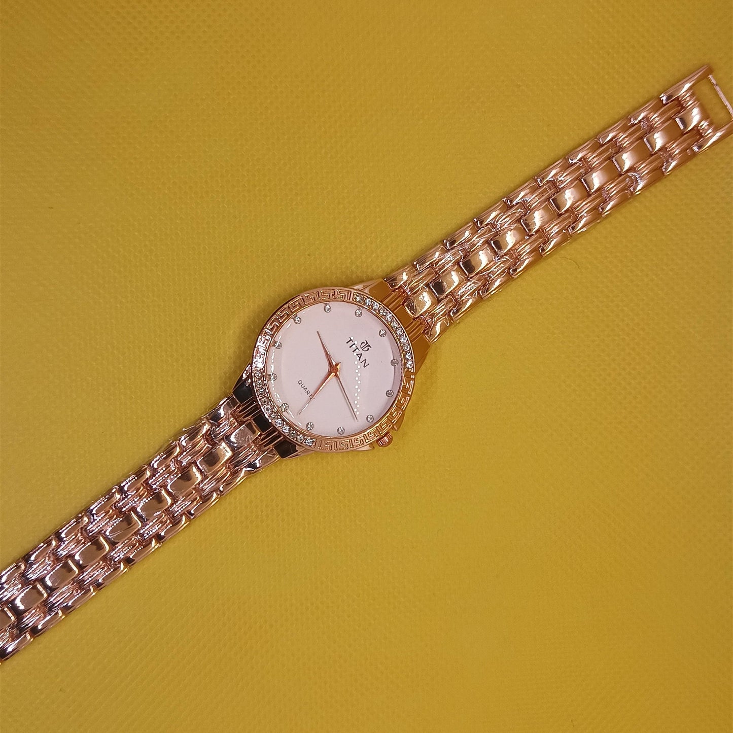 Rose gold watch with a white face on a yellow background