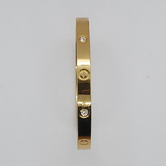 Gold bracelet with a black section on a light gray background