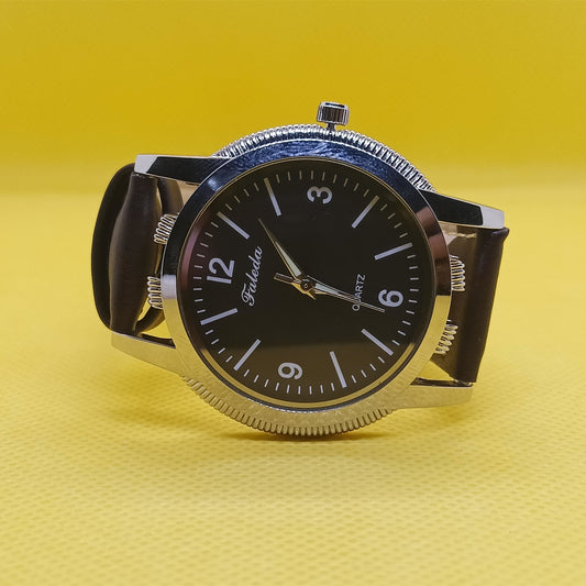 Wristwatch with black face and silver case on a yellow background