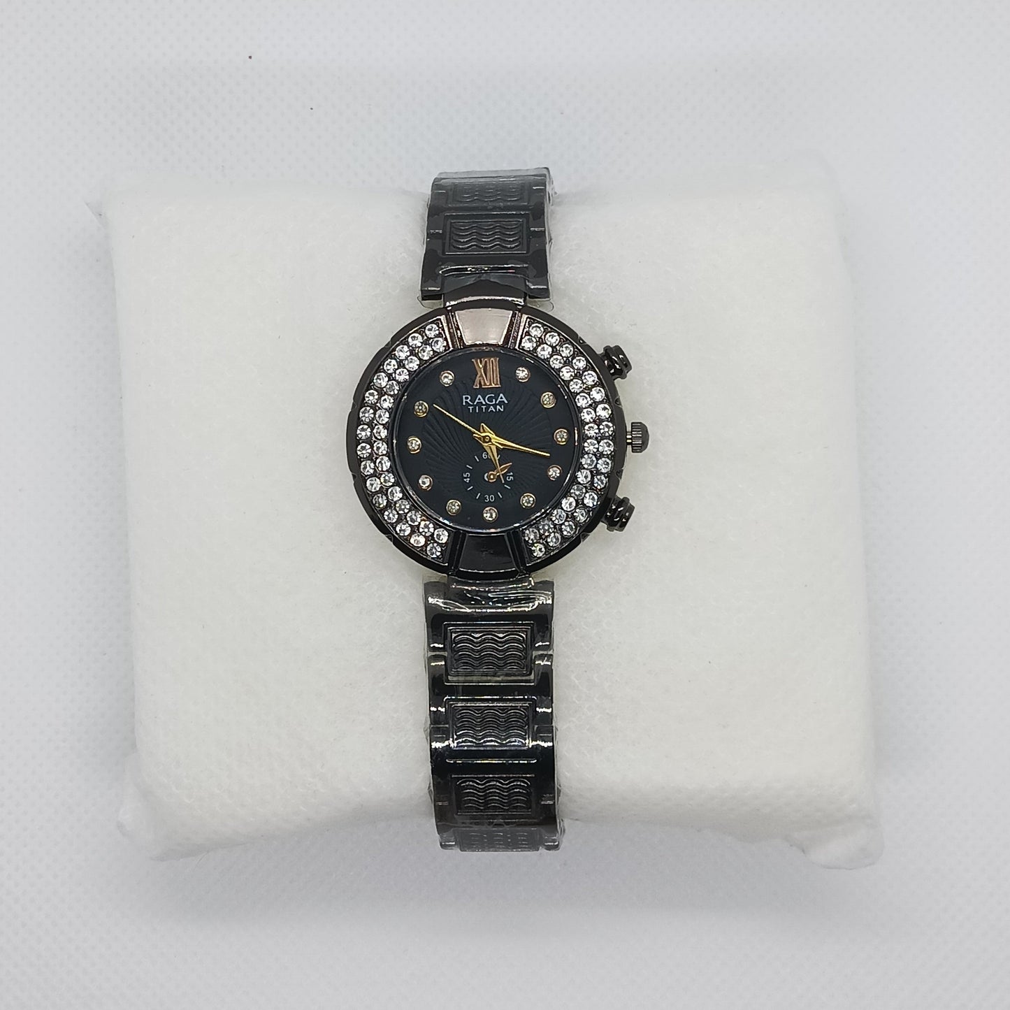 Black wristwatch with diamond accents on a white cushion against a light gray background