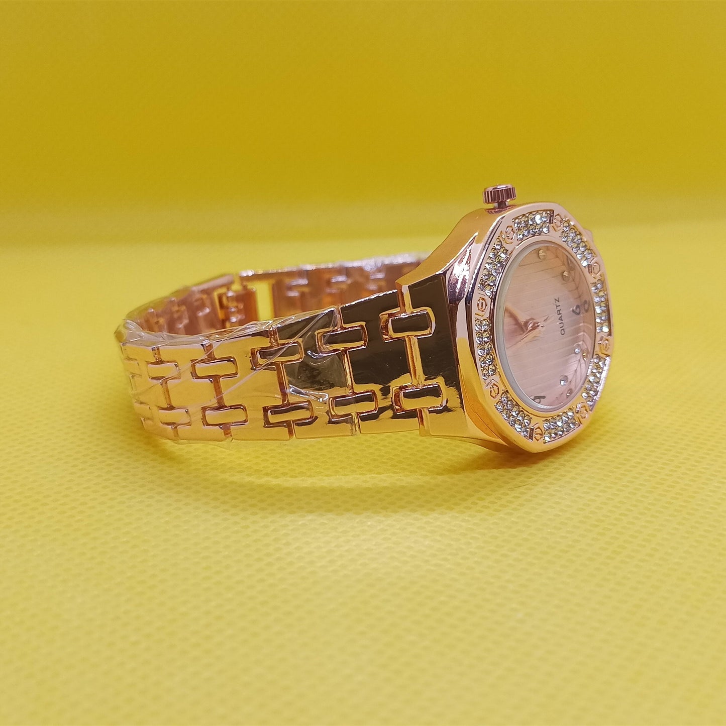 Gold watch with diamond-studded face on a yellow background