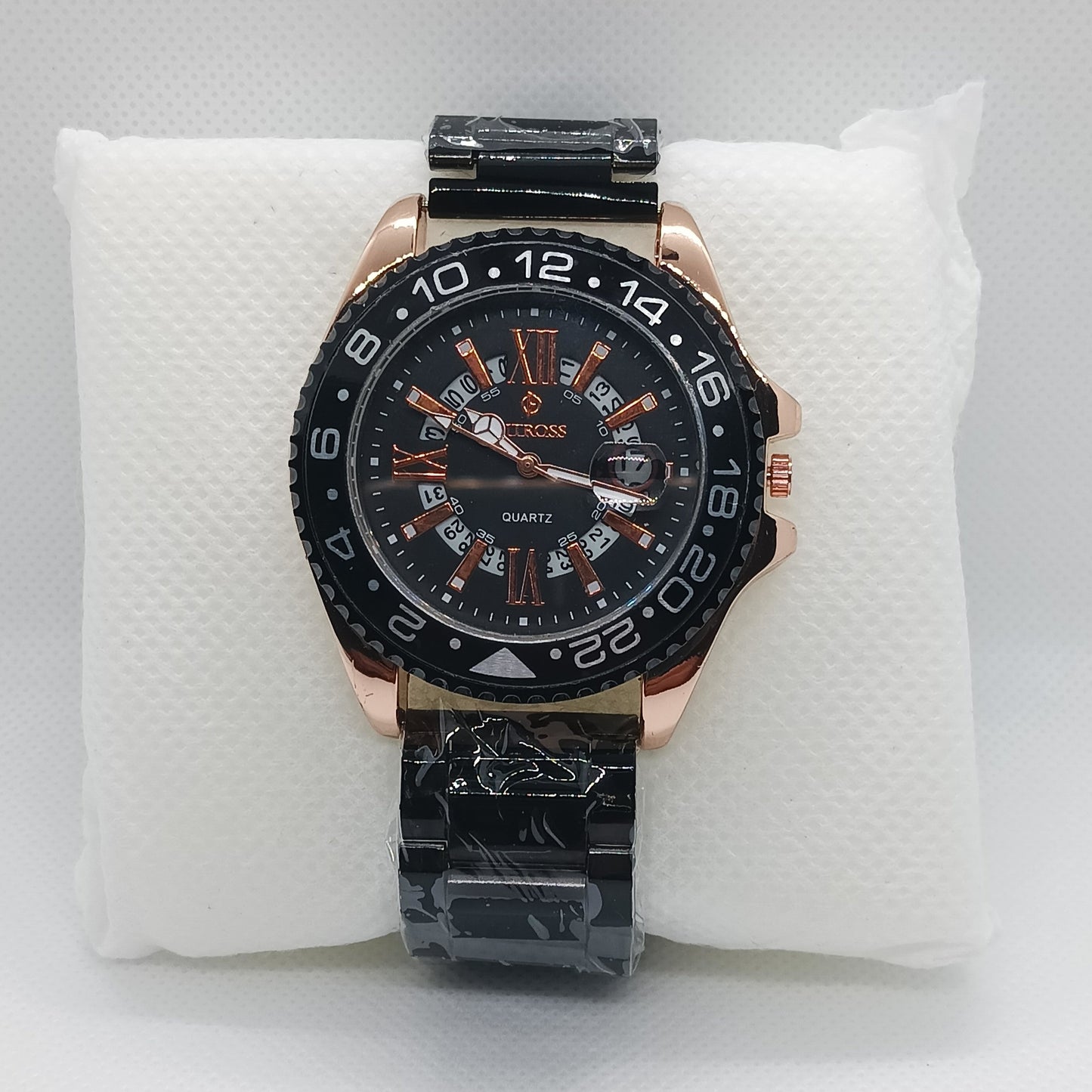 Luxury watch with black and rose gold design on a white cushion
