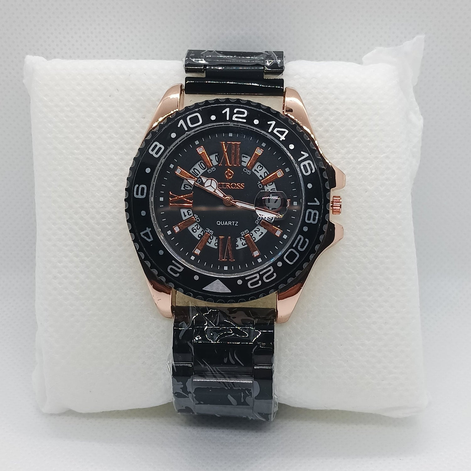 Luxury watch with black and rose gold design on a white cushion