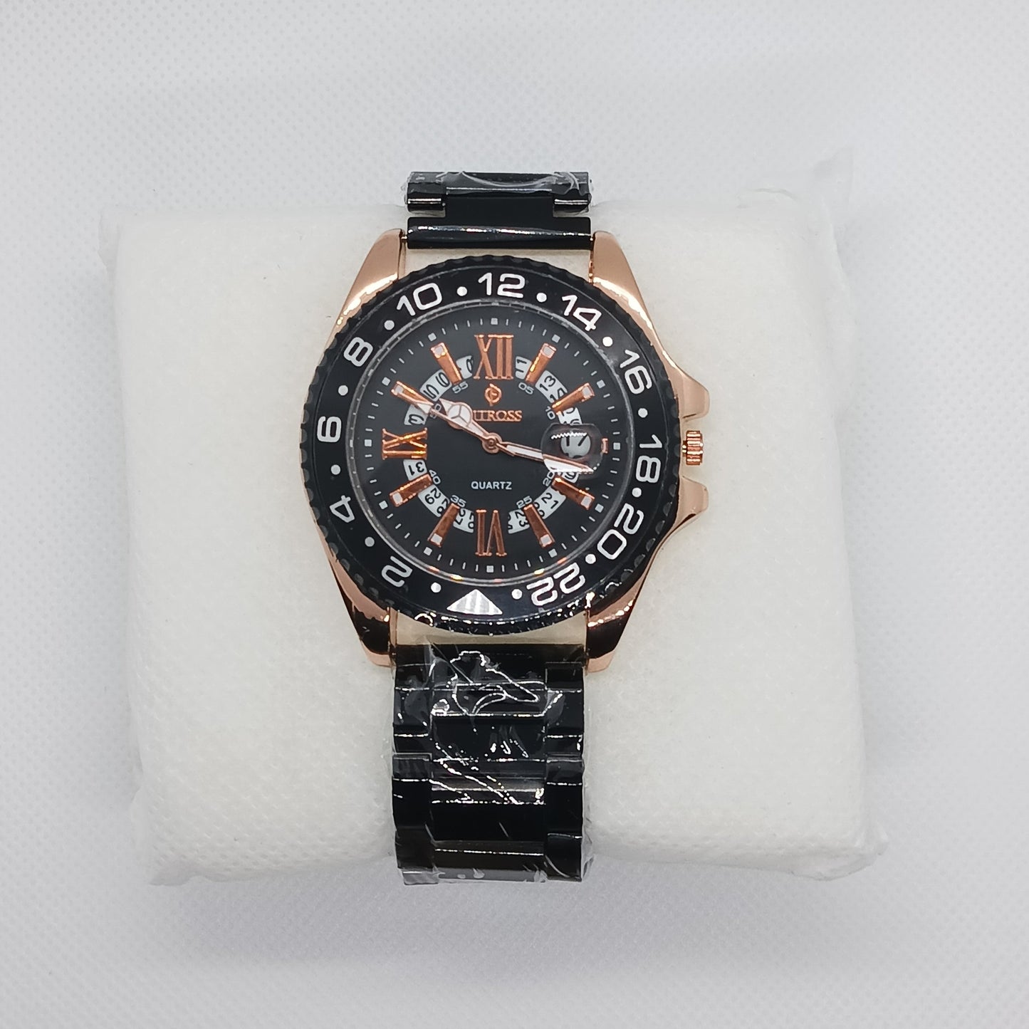Wristwatch with black and rose gold design on a white cushion