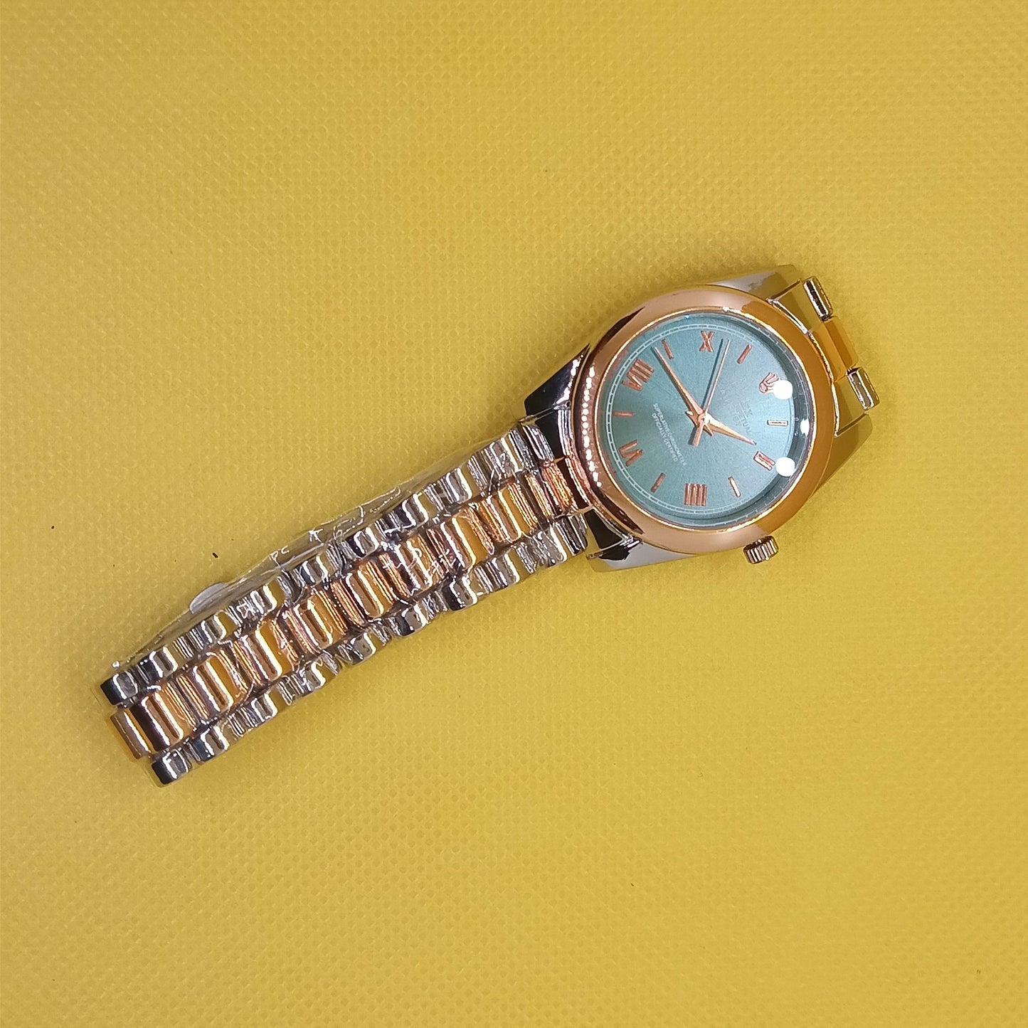Wristwatch with a gold and silver band on a yellow background