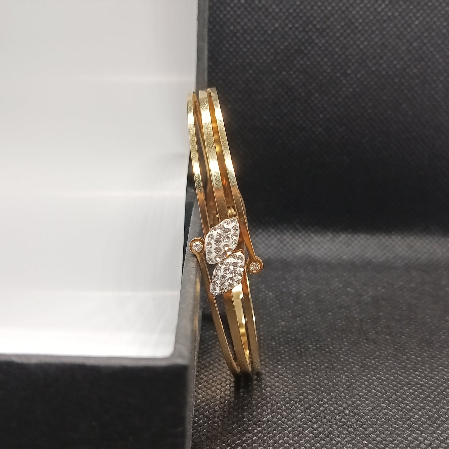 Gold bracelet with diamond accents on a black surface