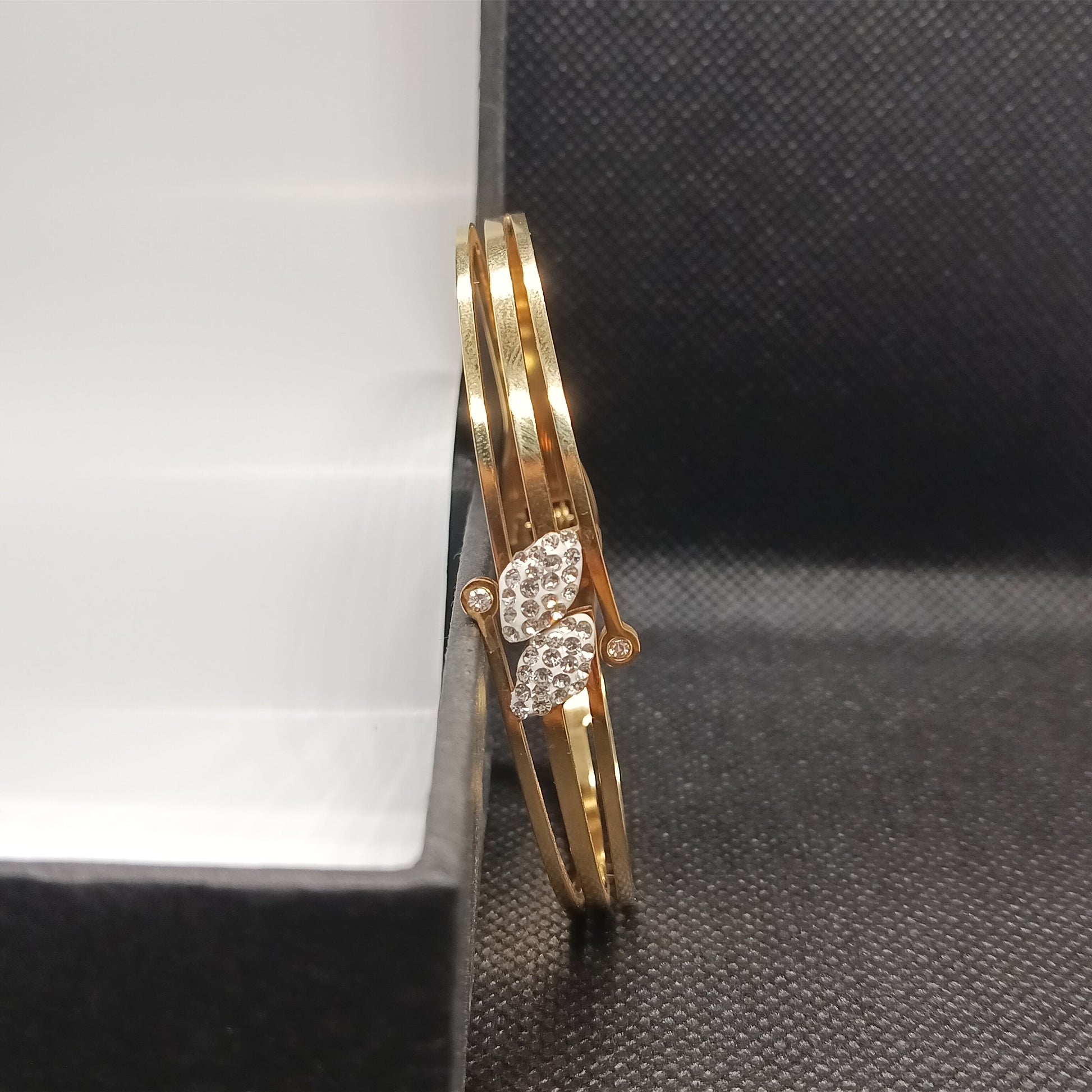 Gold bracelet with diamond accents on a black surface