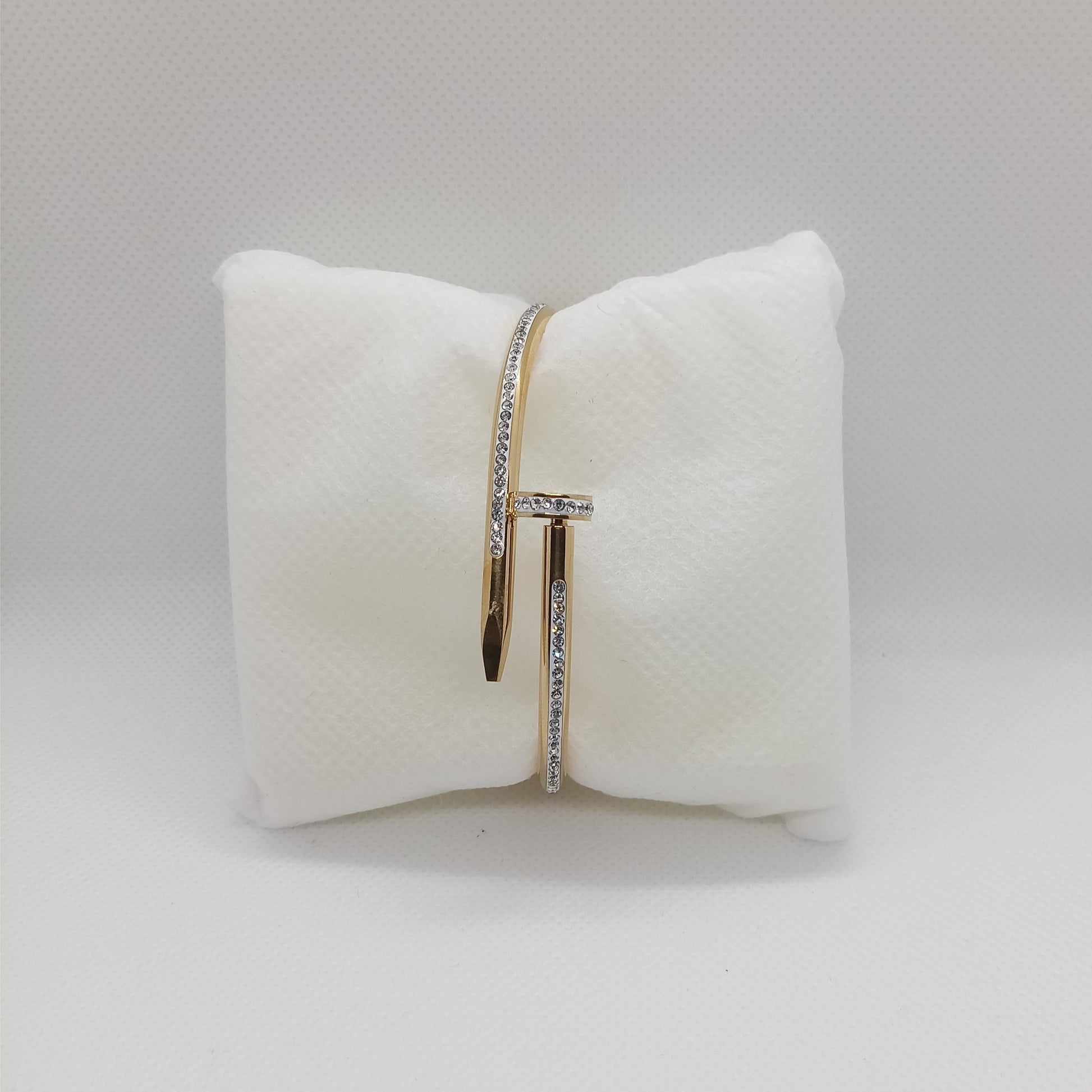 Gold ring with diamonds on a white bow-shaped pillow against a gray background
