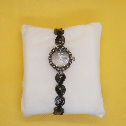 Decorative watch on a white cushion against a yellow background