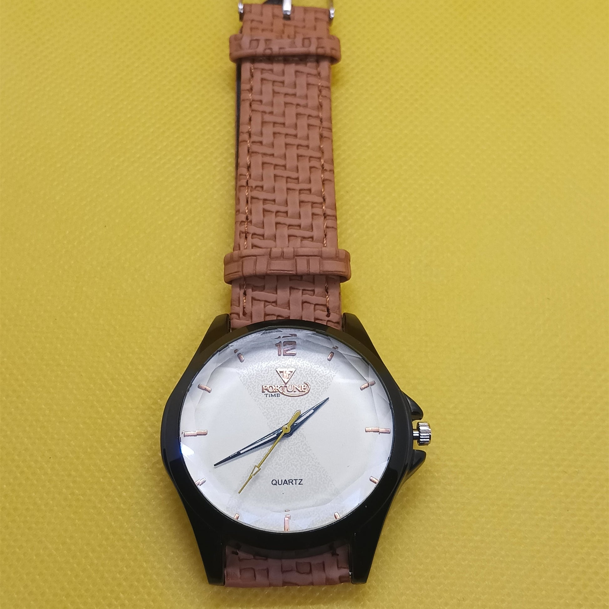 Wristwatch with brown strap and white face on a yellow background