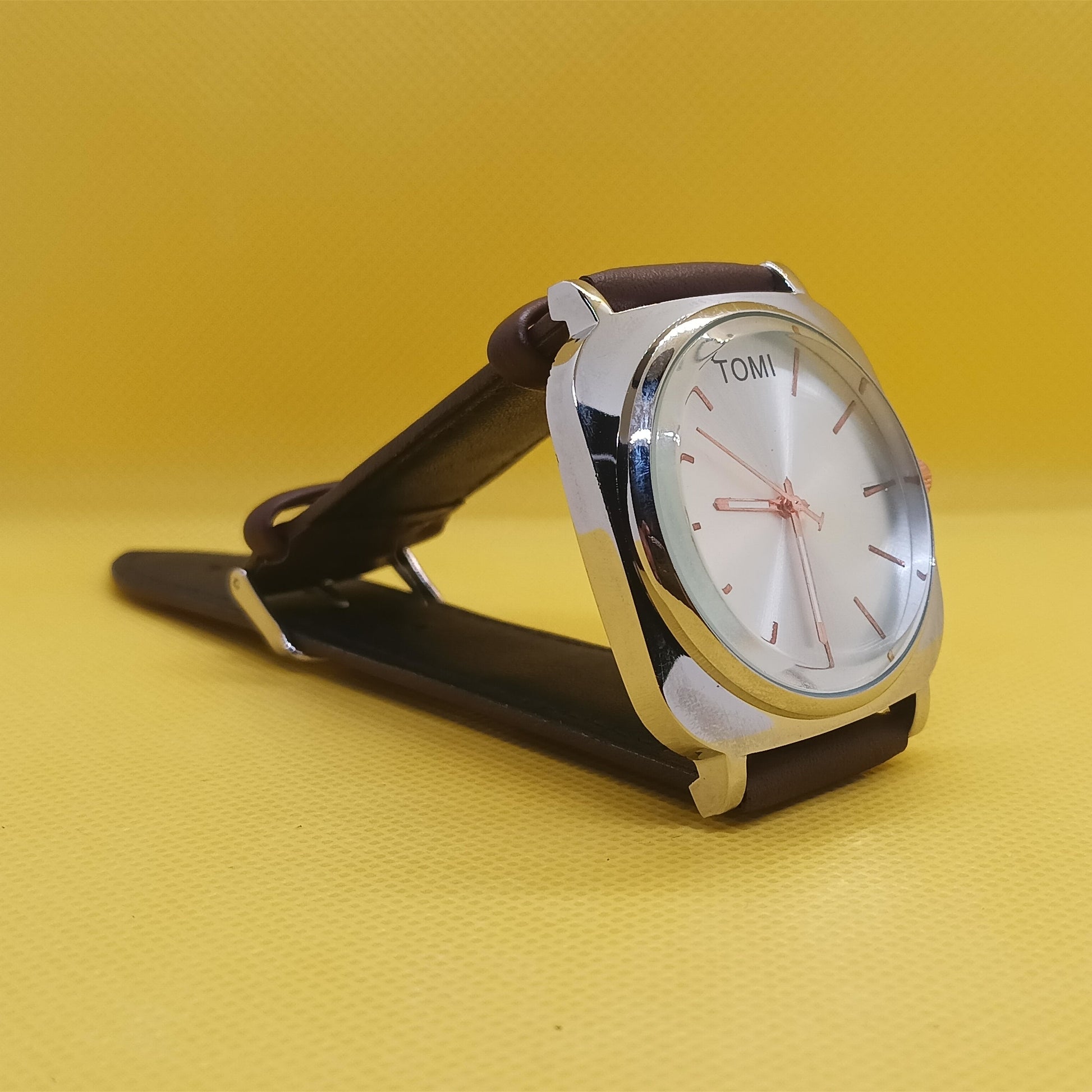 Watch with a brown strap on a yellow background