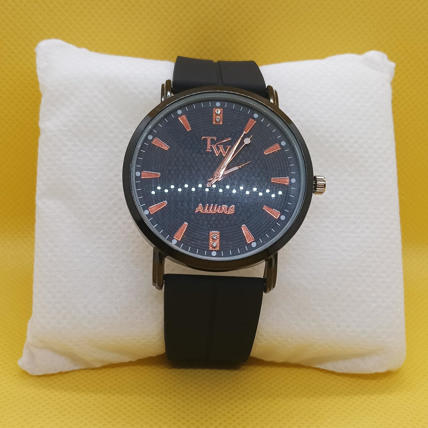 Watch with black strap and blue face on a white cushion against a yellow background