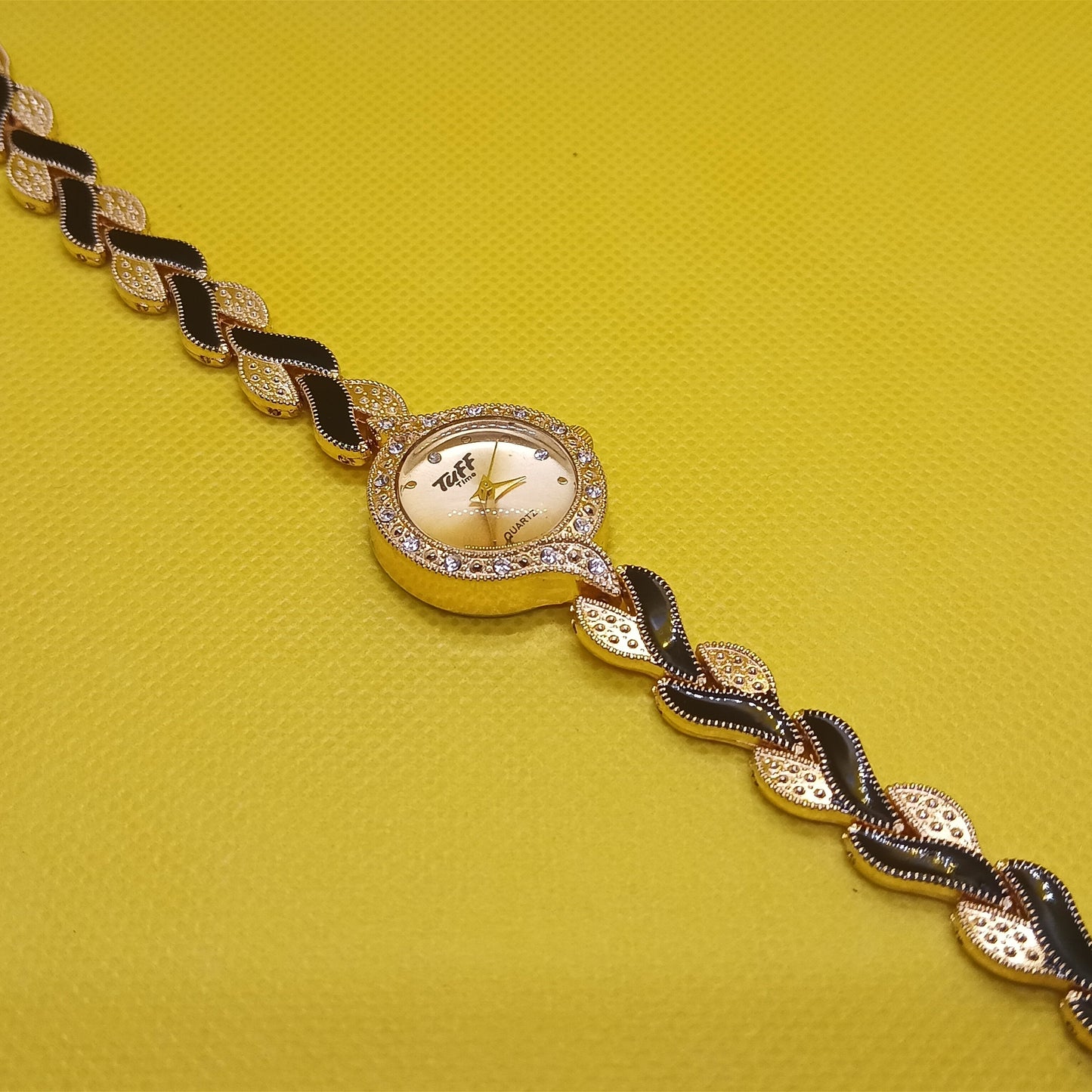Gold and black bracelet on a yellow background