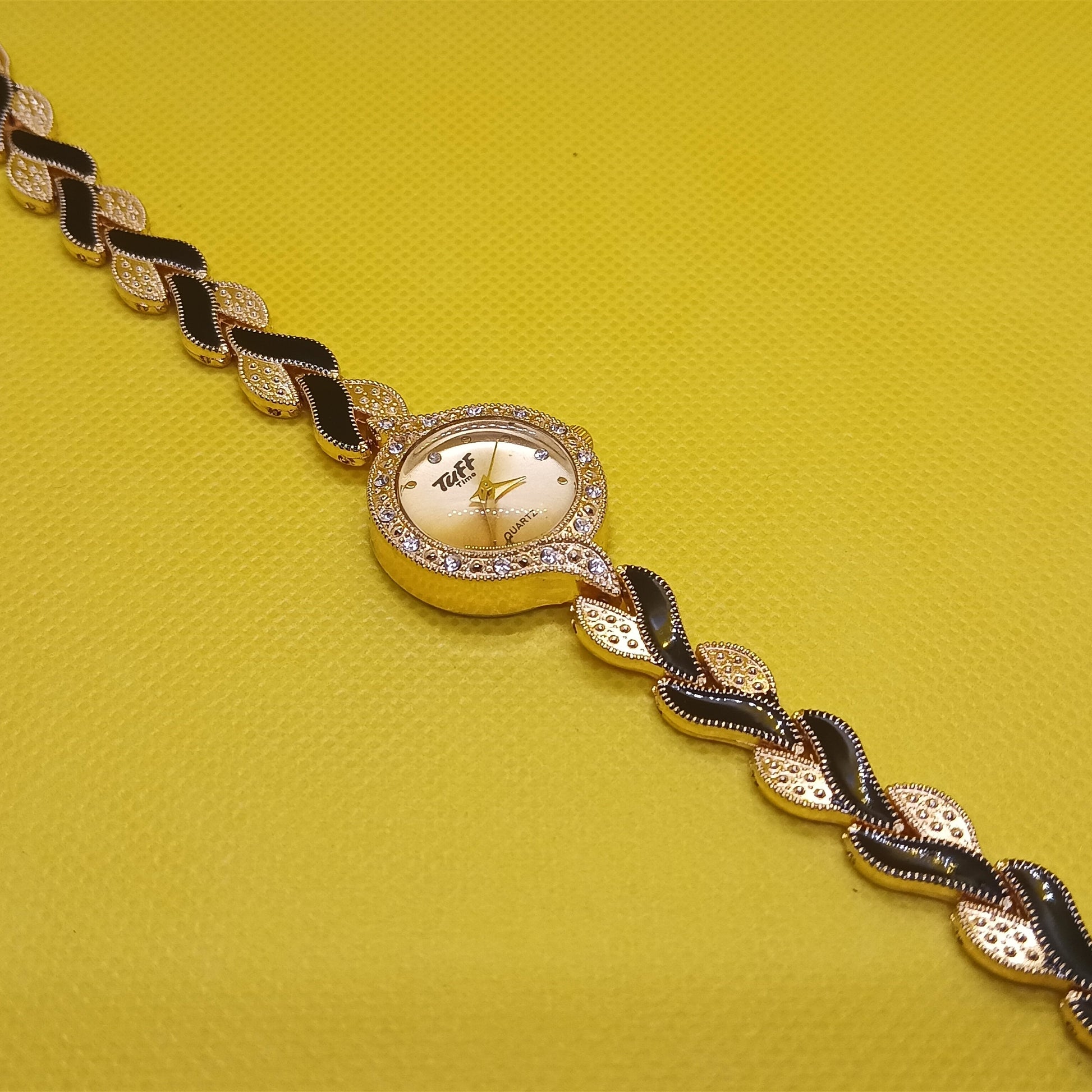 Gold and black bracelet on a yellow background