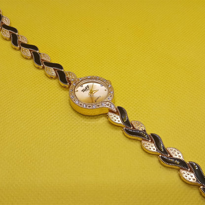 Gold and black bracelet on a yellow background
