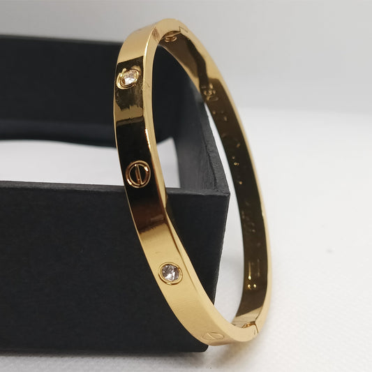 Gold bracelet with diamond accents on a black stand against a light gray background