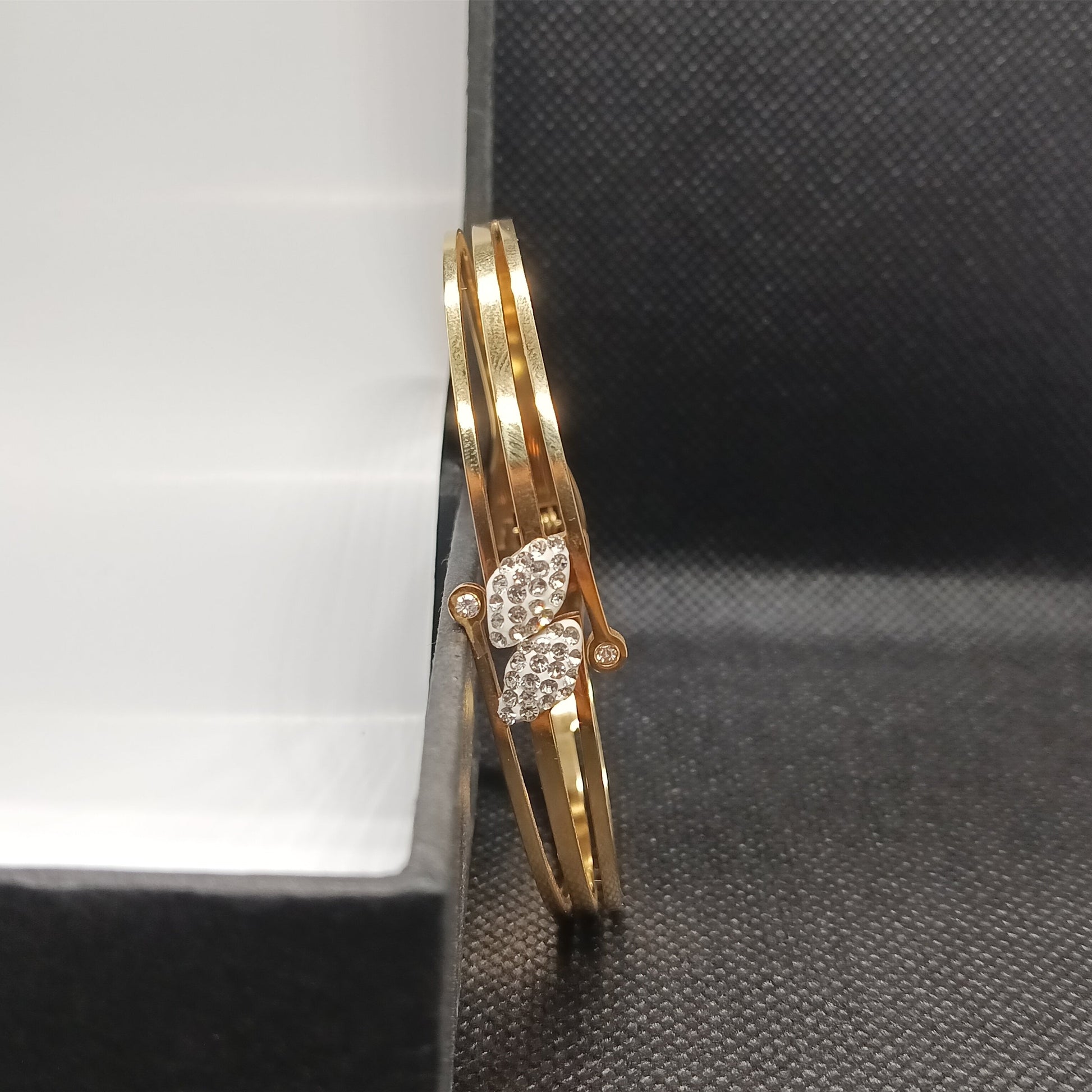 Gold bracelet with diamond accents on a textured black surface