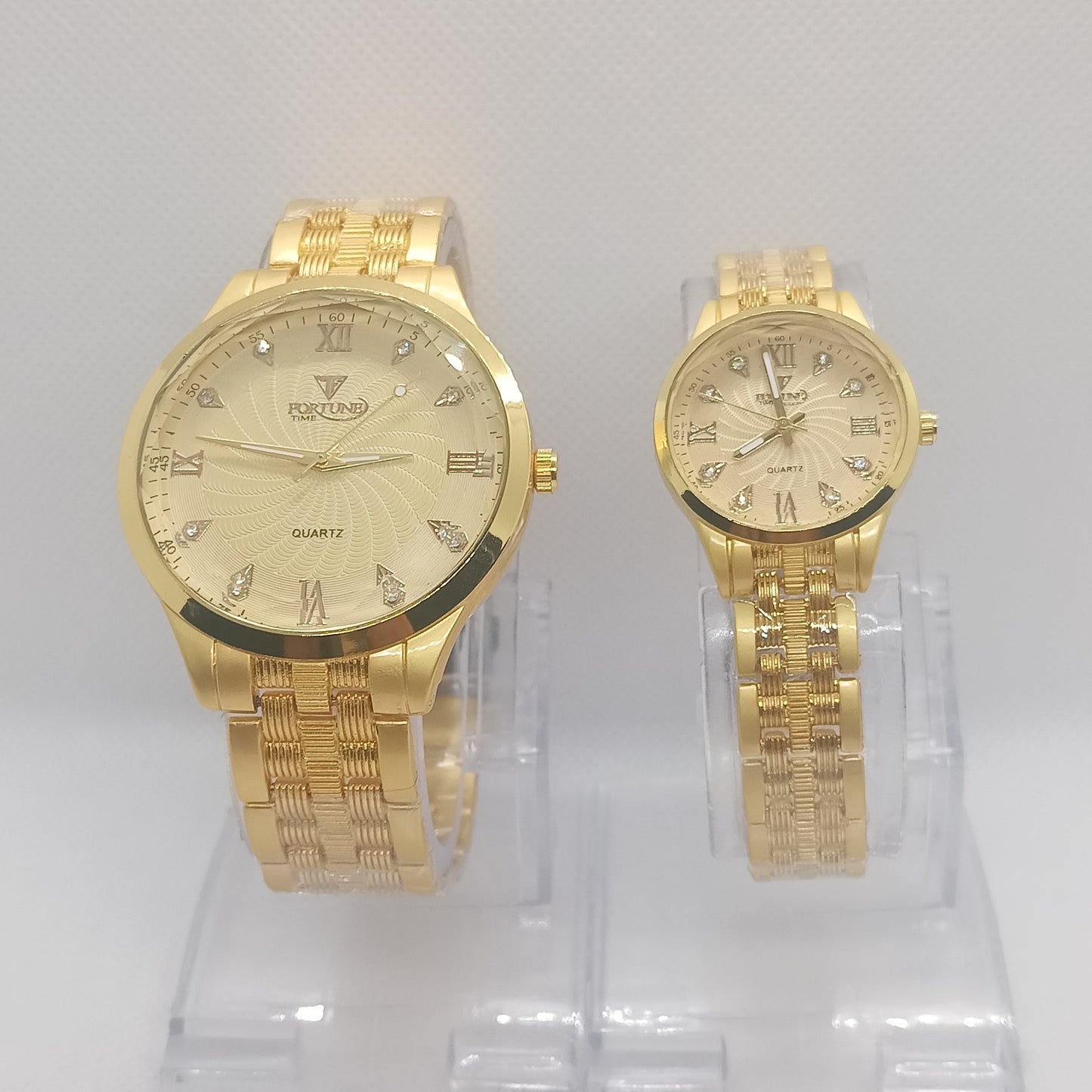 Two gold watches on a clear plastic stand against a white background