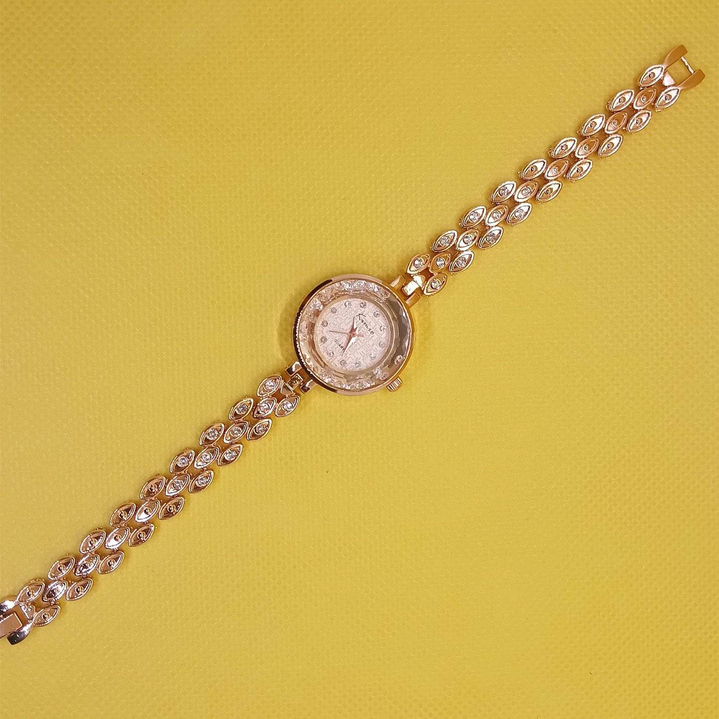 Gold wristwatch with a chain strap on a yellow background