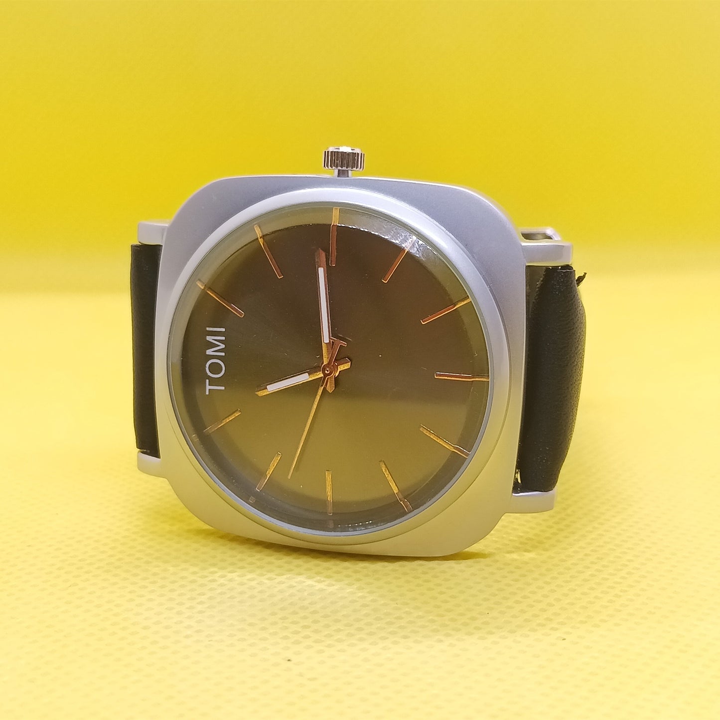 Watch with a brown face and black strap on a yellow background