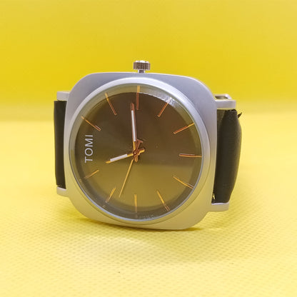 Watch with a brown face and black strap on a yellow background
