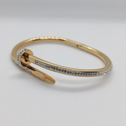 Gold bracelet with small stones on a light gray background