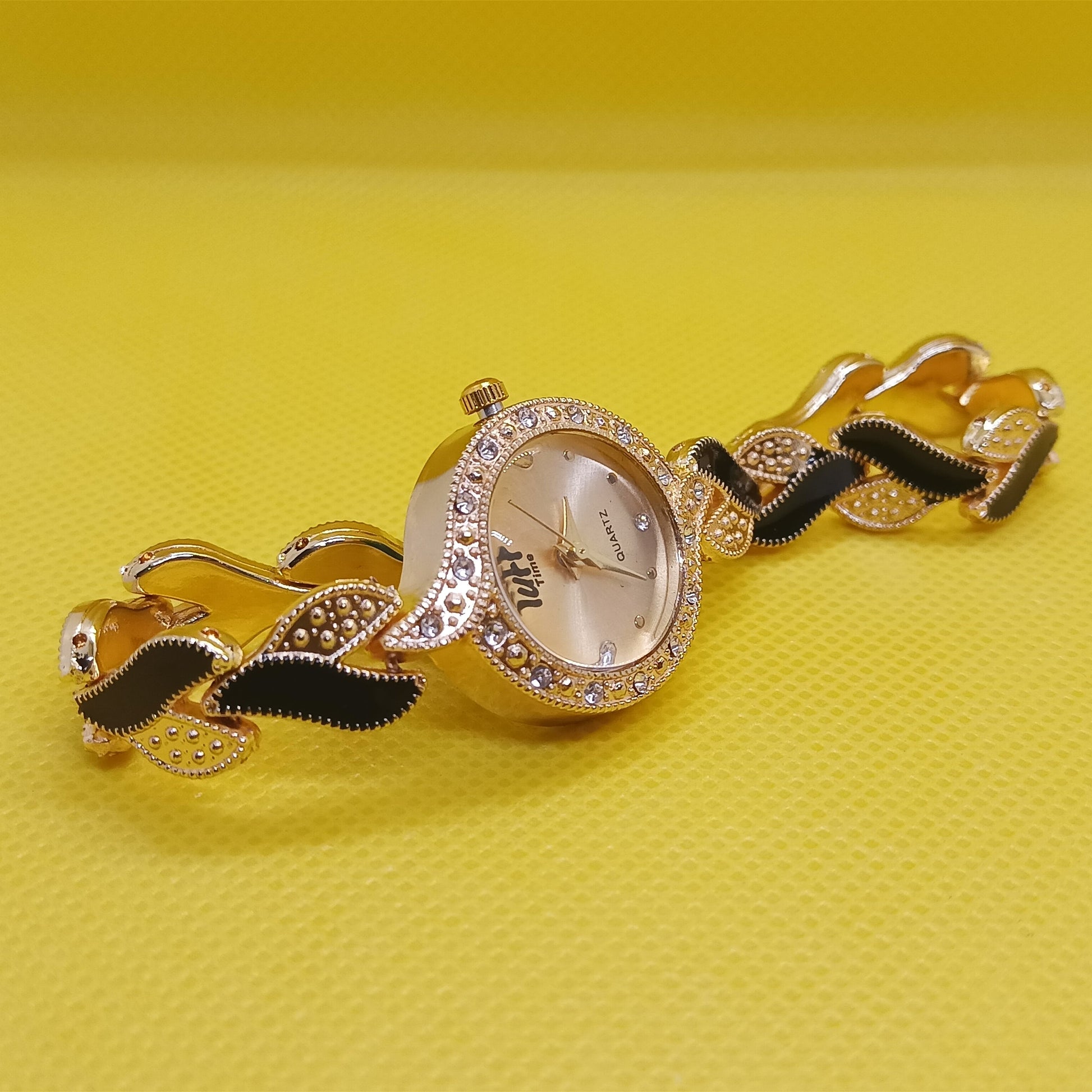 Gold watch with decorative band on a yellow background