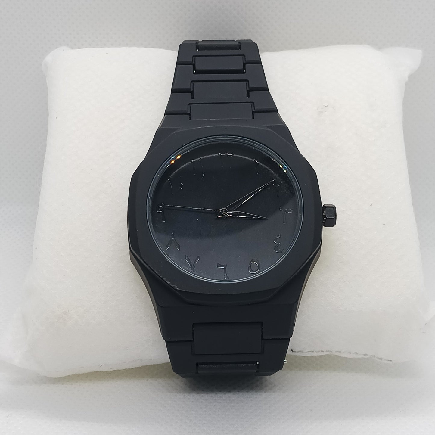 Black watch on a white cushion with a light gray background
