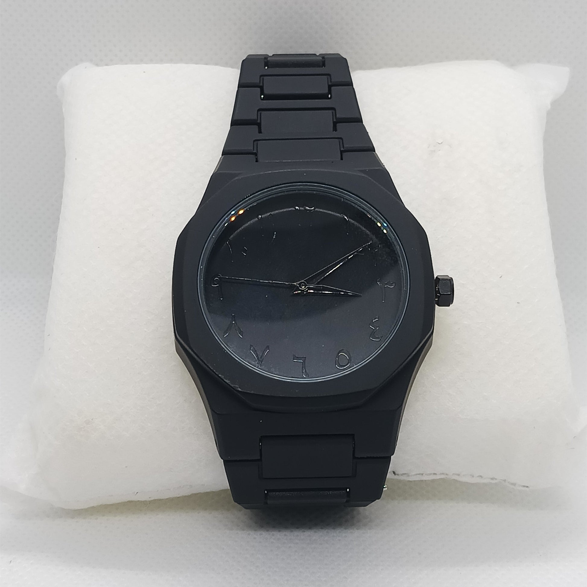 Black watch on a white cushion with a light gray background