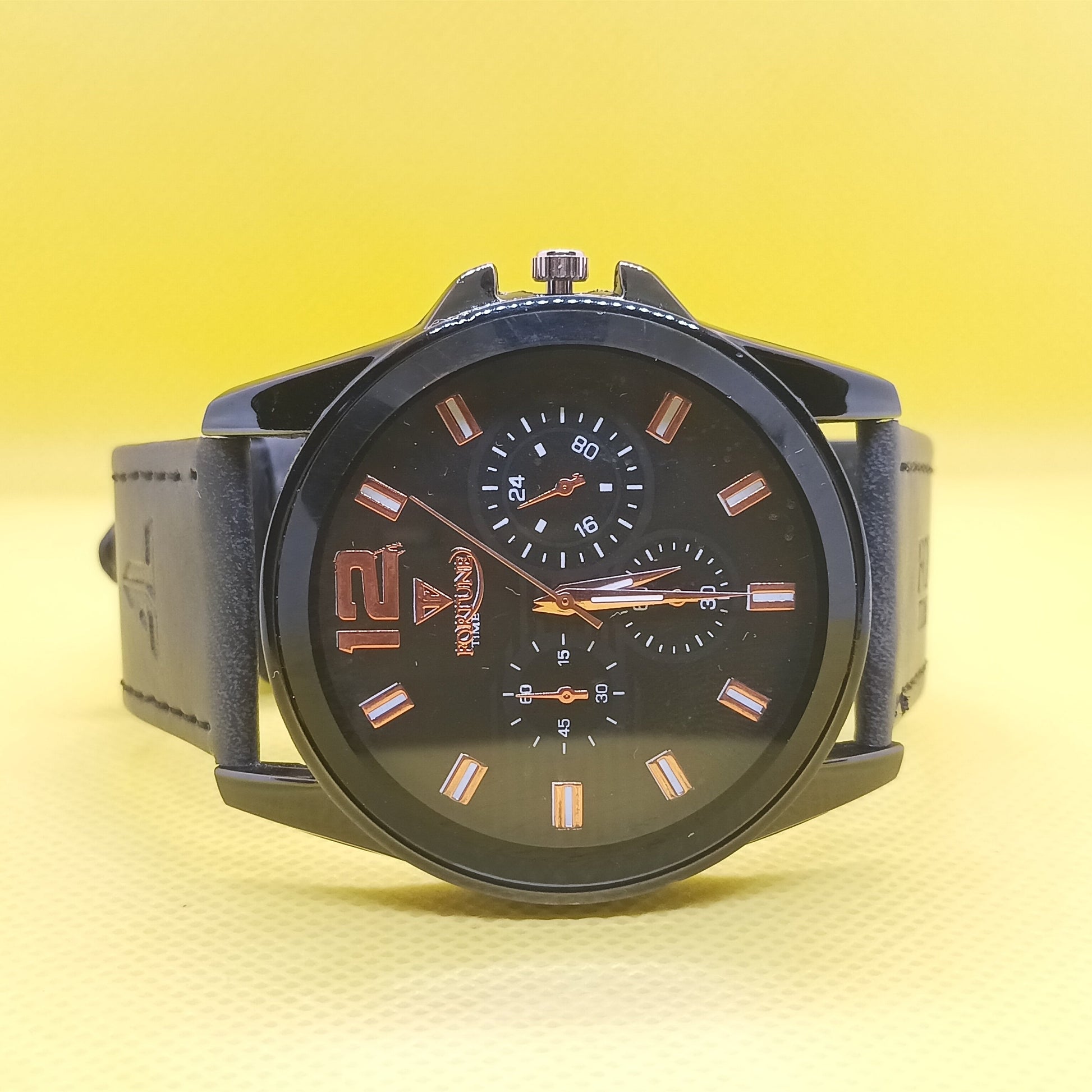 Black wristwatch with a detailed face on a yellow gradient background