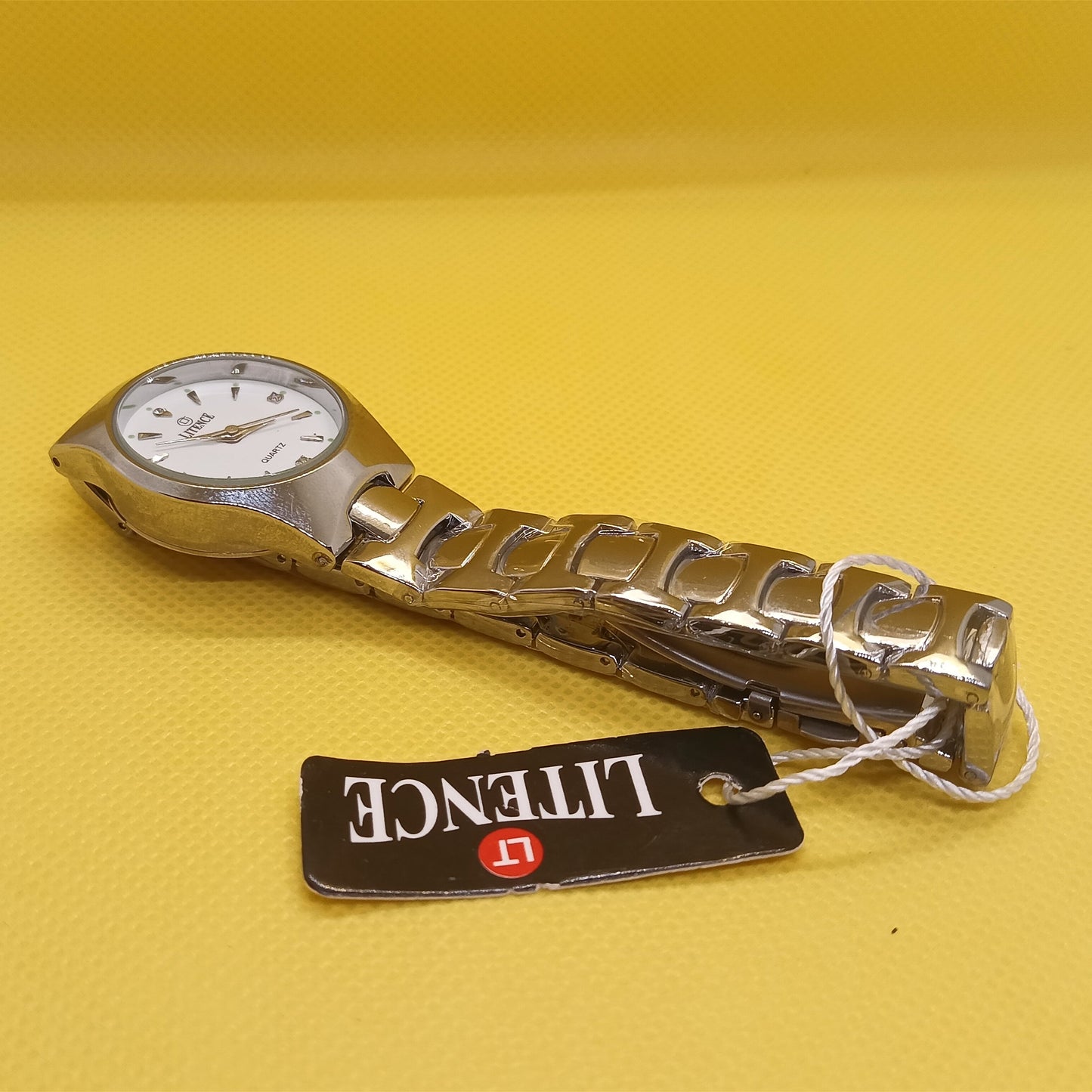 Metallic watch with a visible brand tag on a yellow background