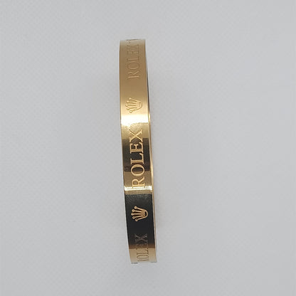 Gold bracelet with 'Rolex' engraving on a light gray background