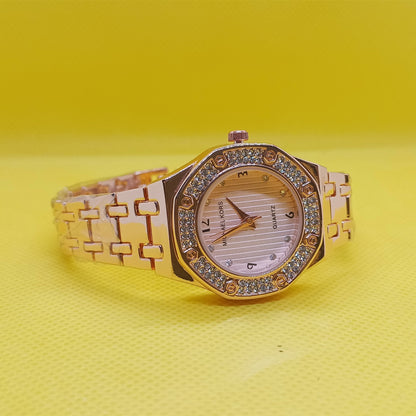 Gold wristwatch with gemstone accents on a yellow background