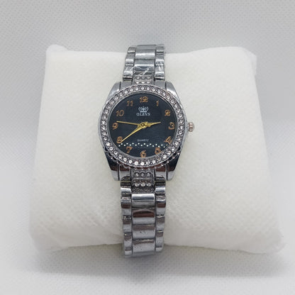 Silver watch with a black face on a white cushion against a light gray background