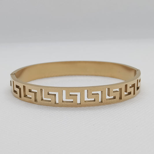 Gold bracelet with geometric pattern on a light gray background