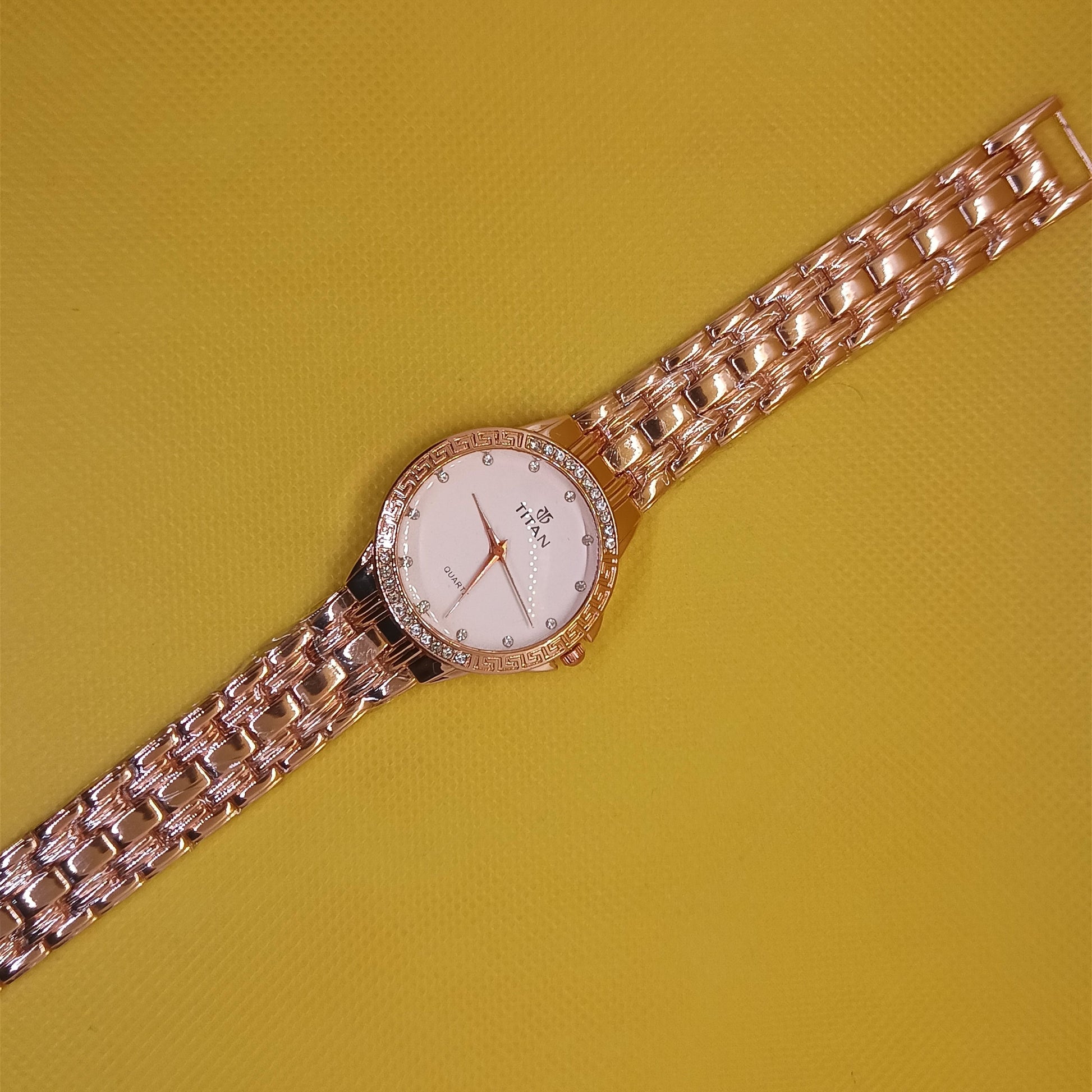 Rose gold watch with a white face on a yellow background