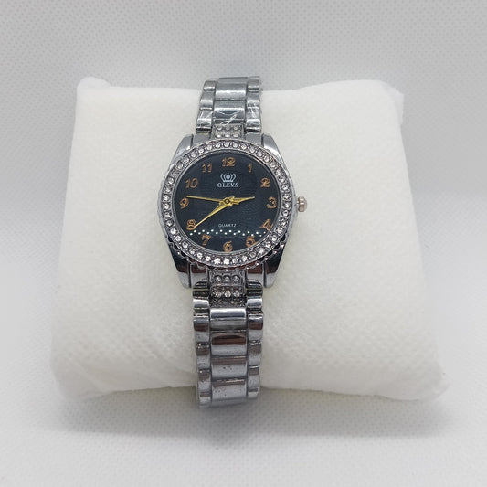 Silver watch with a black face on a white cushion against a light gray background