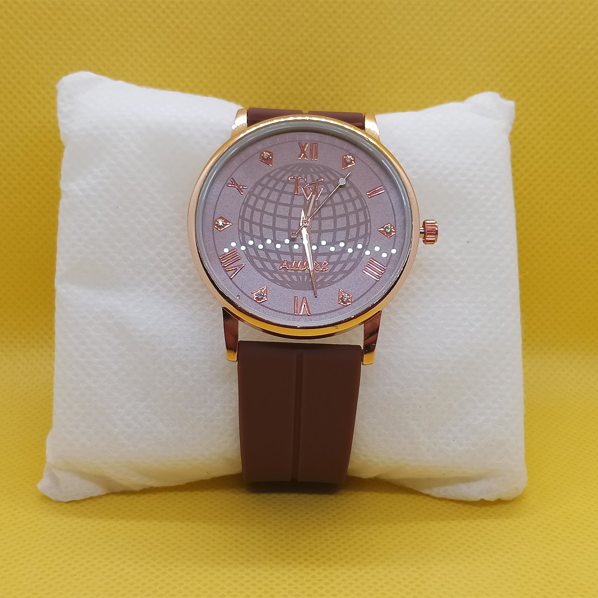 Watch with a brown strap and gold case on a white cushion against a yellow background