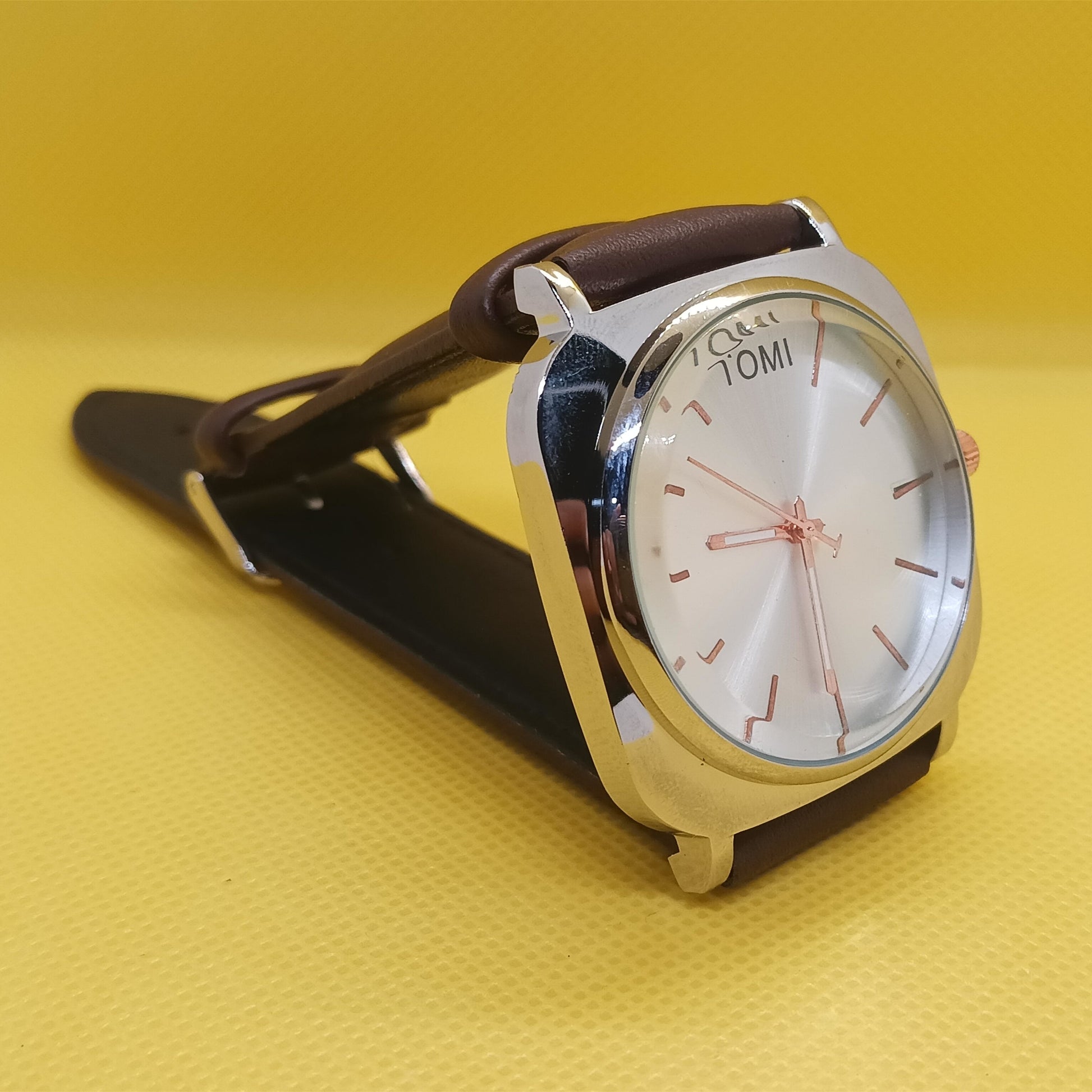Watch with a brown strap on a yellow background